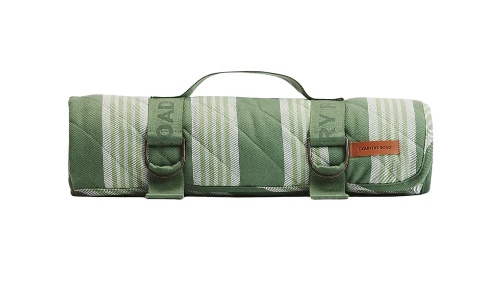 A rolled up picnic blanket with straps that has a green and white striped design.