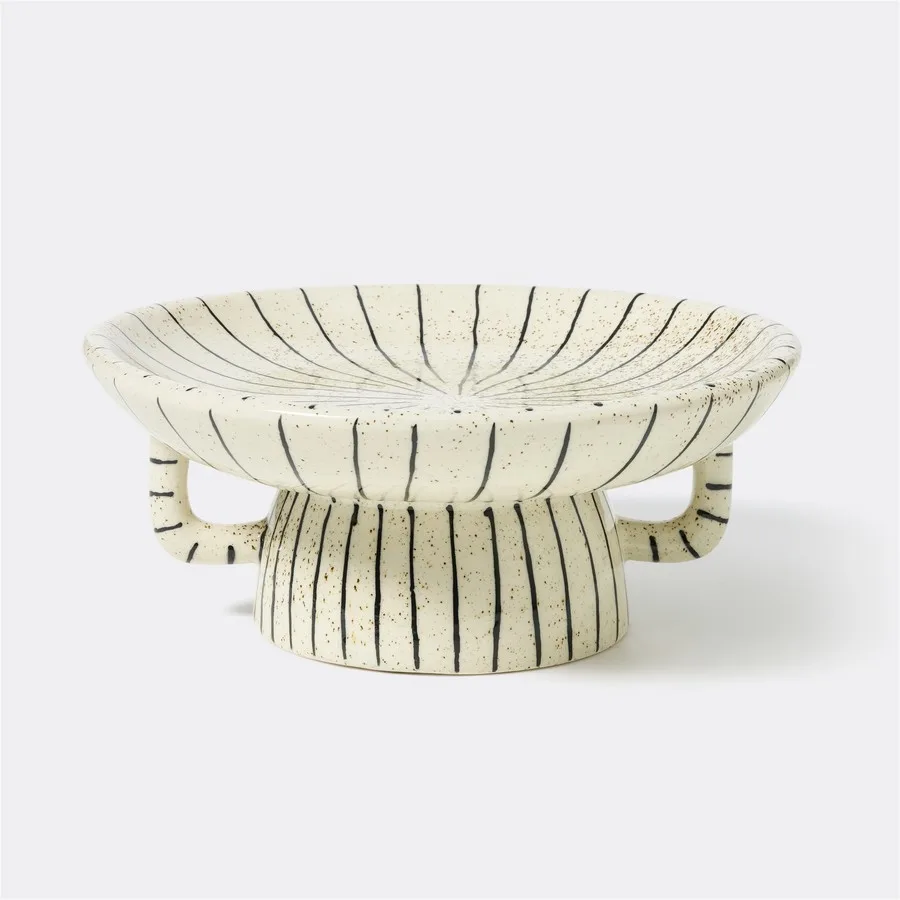 This unique piece features a shallow, wide bowl on a round pedestal base, complete with two integrated loop handles. Perfect for displaying small trinkets, holding jewellery, or serving as a distinctive decorative accent.