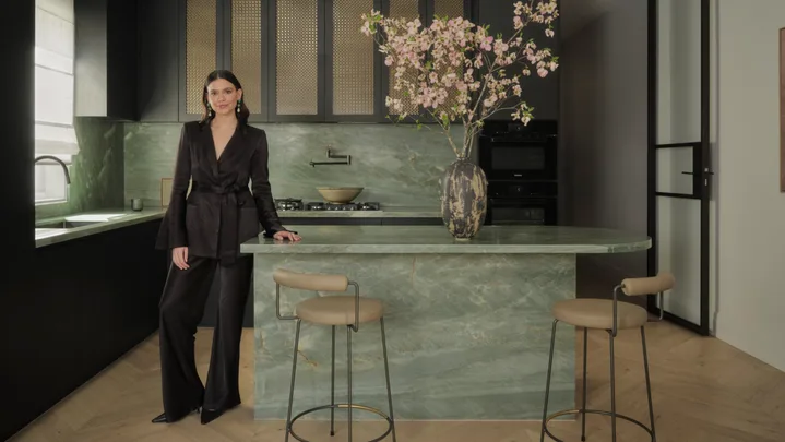 Briellyn Turton interior designer stands in a kitchen with a green marble island bench topped with cherry blossom flowers