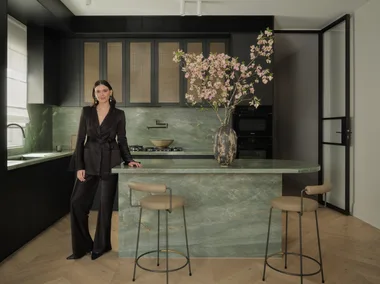 Briellyn Turton interior designer stands in a kitchen with a green marble island bench topped with cherry blossom flowers