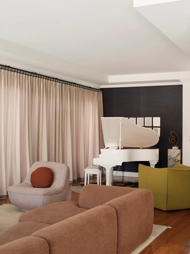 Luxurious living room with a white grand piano, brown sofas, and beige curtains.