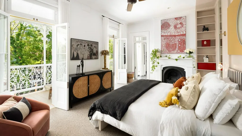 a large white master bedroom with doors onto a balcony in John Aiken's home