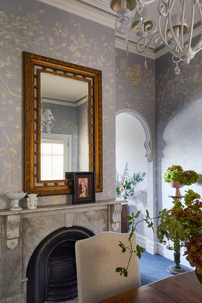 An antique rectangle mirror placed in an elegant dining room above a stone fireplace