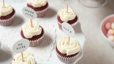Valentine's day recipe of mini red velvet cupcakes with little signs reading 'be mine' and 'love'