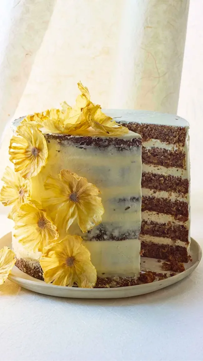 layered hummingbird cake with cream icing and yellow flowers