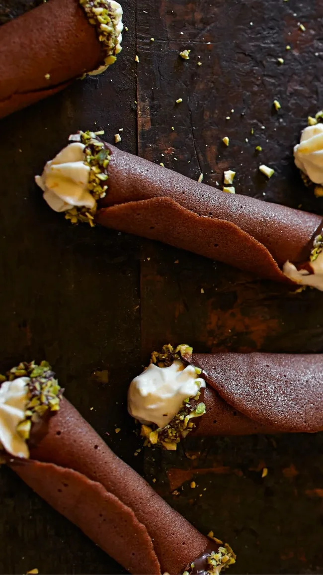 Ricotta & orange cream filled chocolate tuiles displayeded on a wooden board