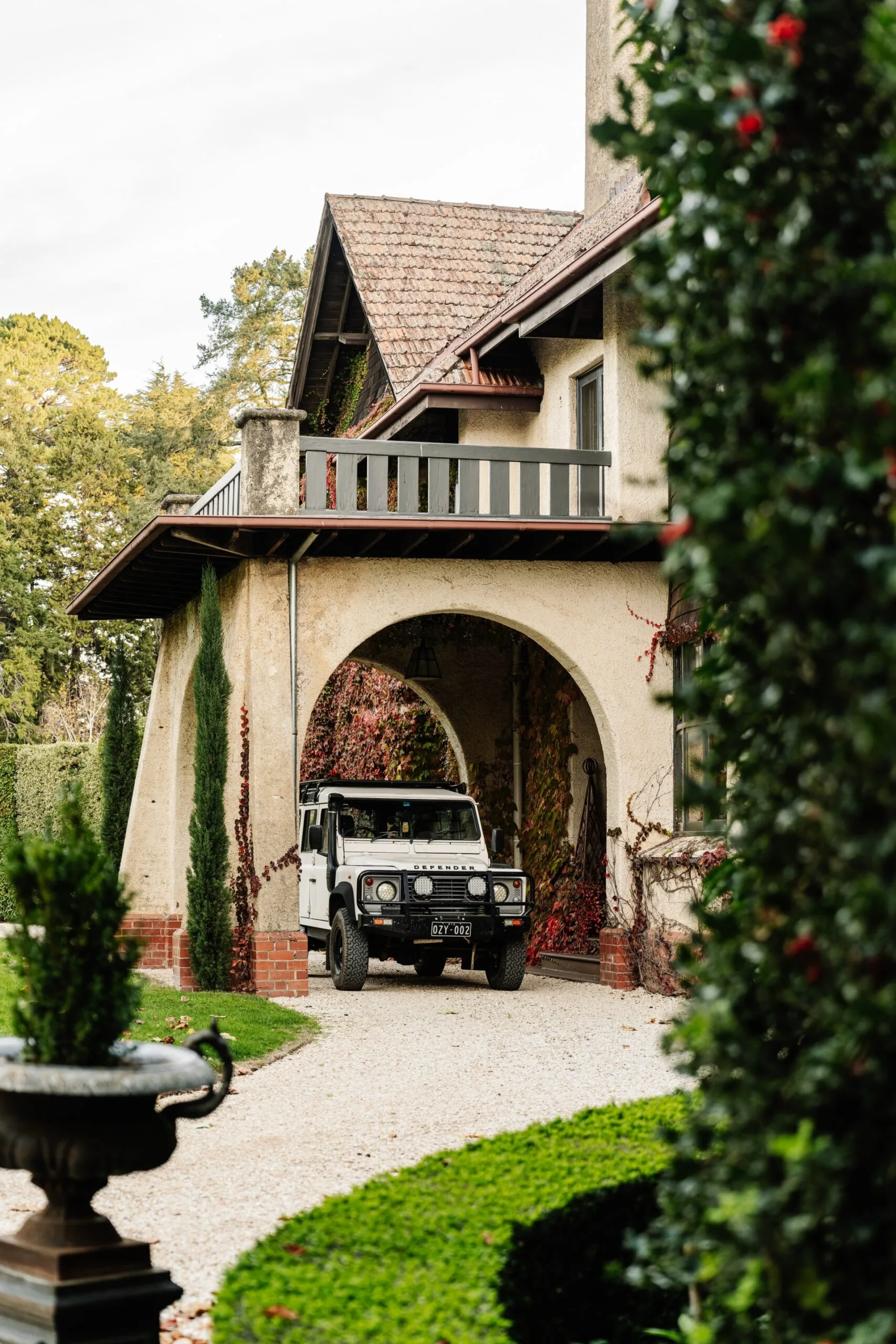 The entrance to the Arts and Crafts style building in Wombat Park Estate in Daylesford. A car is parked underneath a large archway, with a balcony from the second floor above.