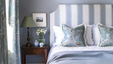 blue feng shui bedroom with blue and white striped bead board and bird patterned cushions
