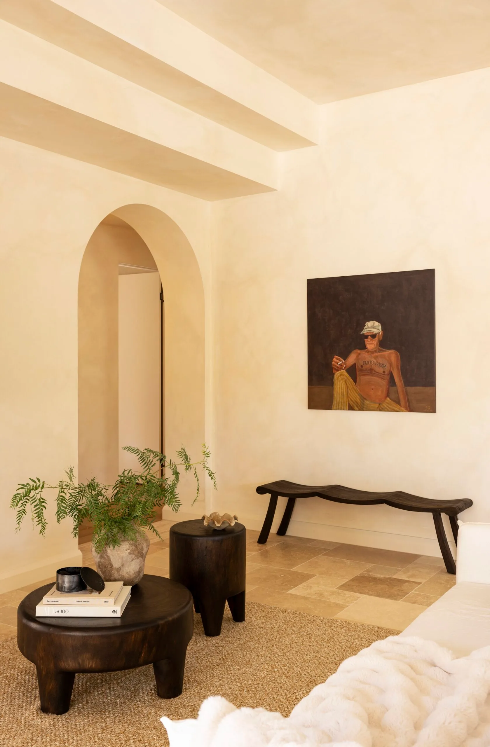 Elegant beige living room with dark wood furniture, an archway, and a painting of a person on the wall.