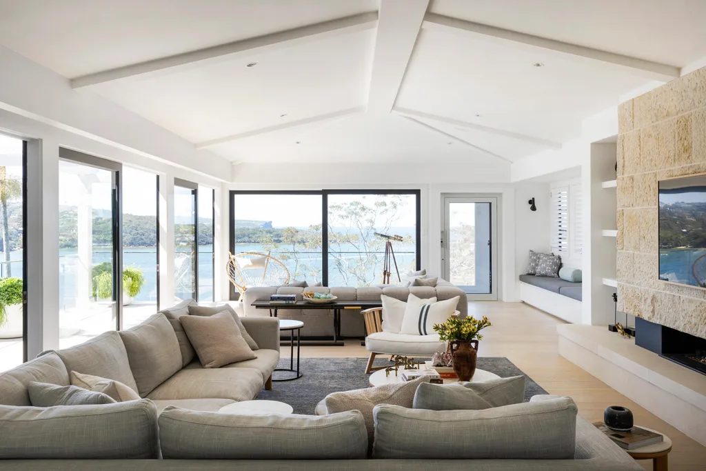 Luxurious living room in a fully renovated and redesigned heritage home with large windows, cosy sofas, and a scenic ocean view in a bright, modern design.