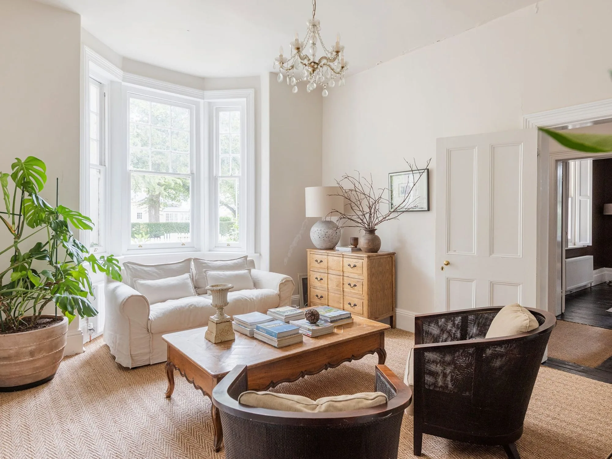 A cream clour living room with bay windows and a small chandelier