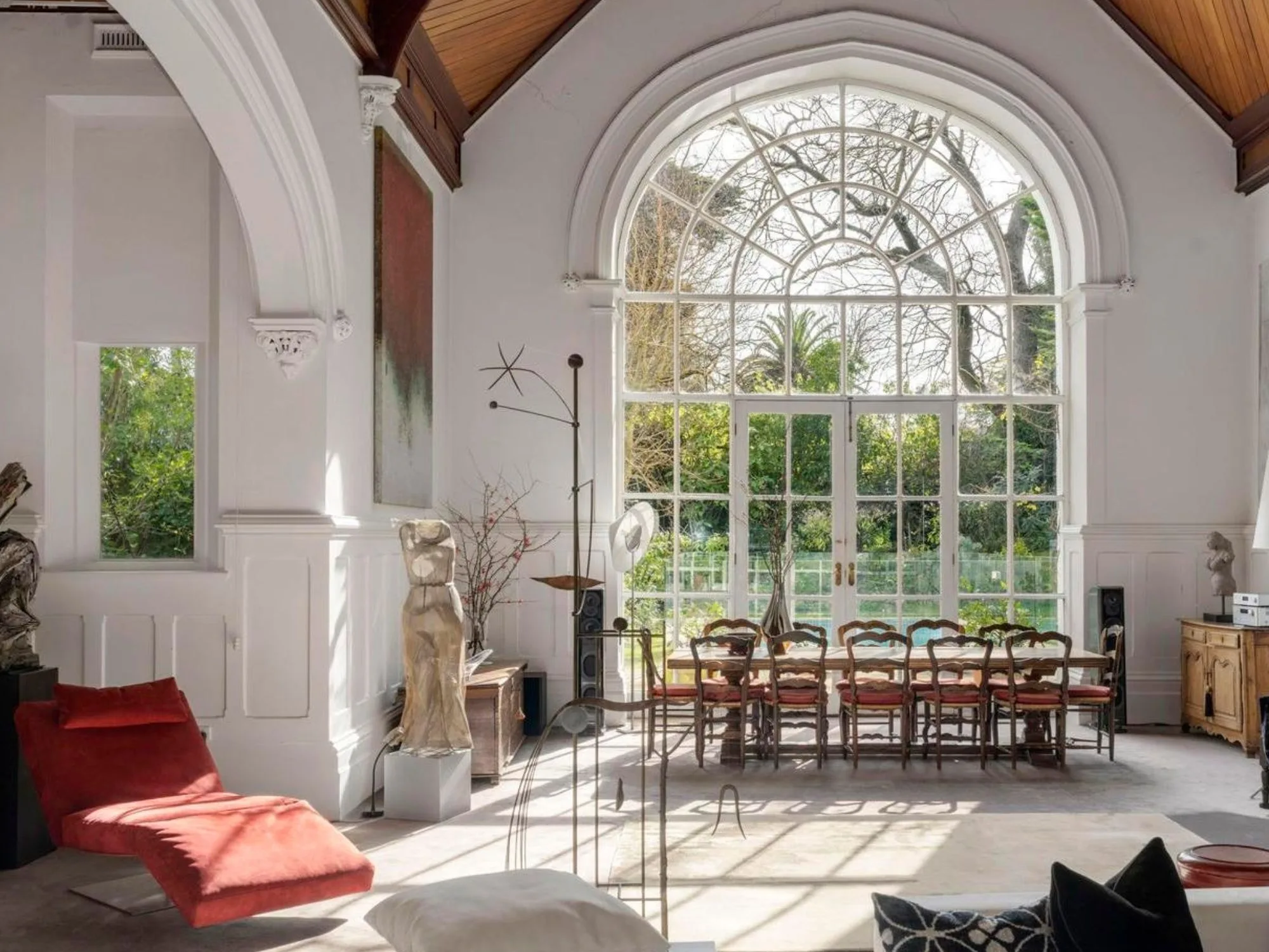 inside Hilton House in Hawthorne with a large arched window and French doors, 12 seat dining table and red daybed lounge