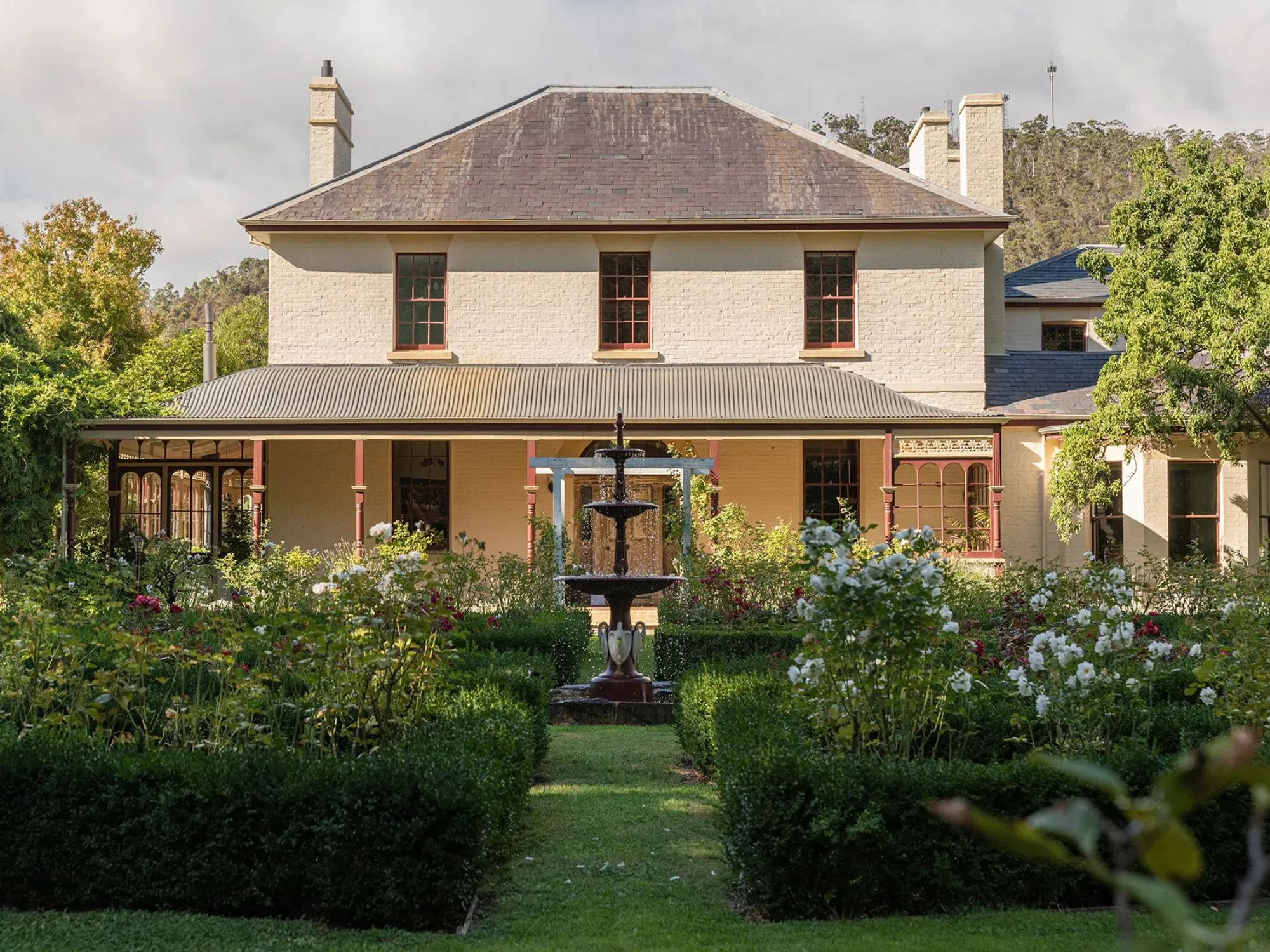 Cream coloured two storey homestead in New Norfolk Tasmania with a fountain and manicured gardens