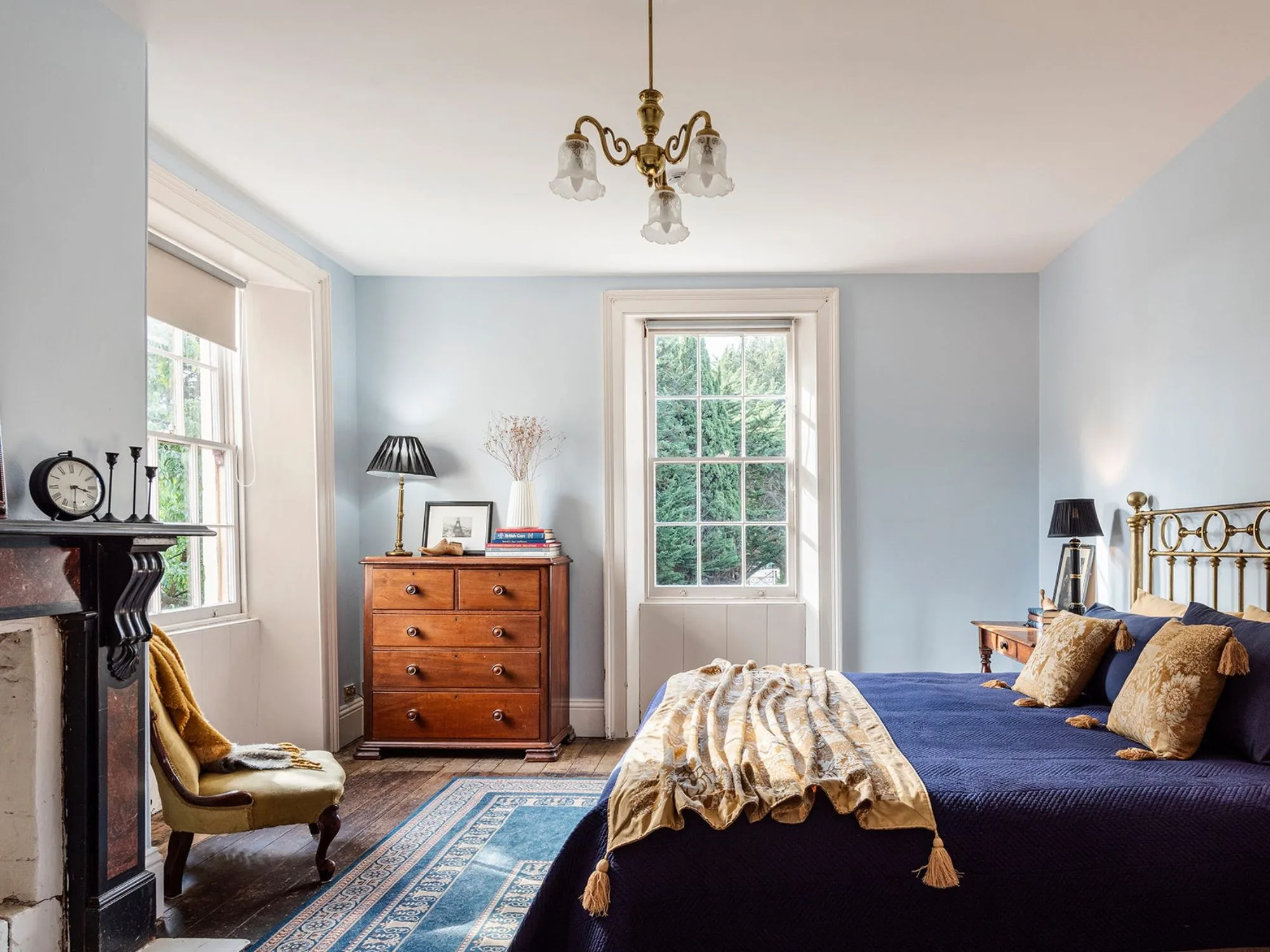 pale blue bedroom with antique brass bed and chandelier at Glen Derwent House in Tasmania