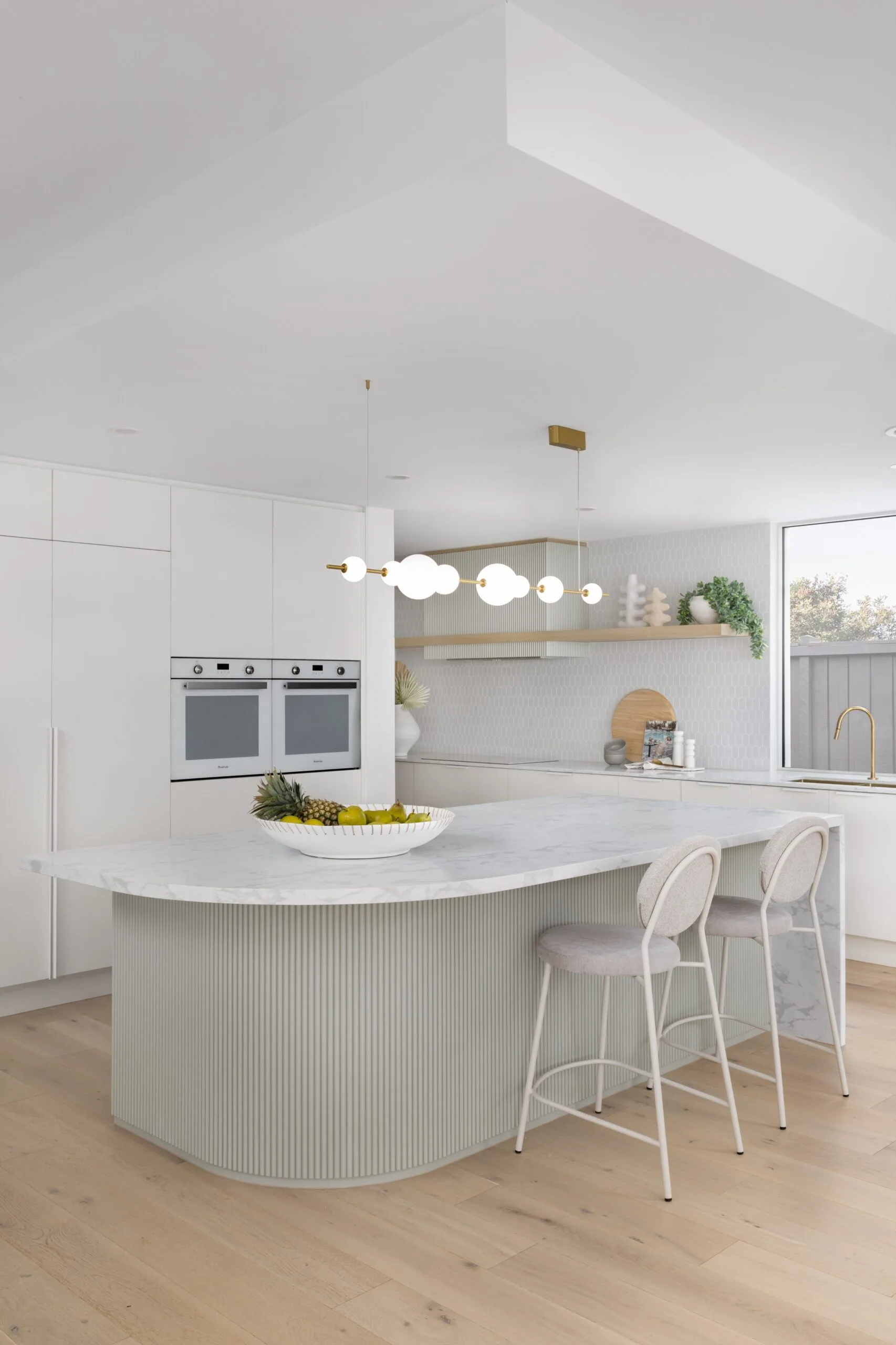 White kitchen with curved stone kitchen kitchen island with pale blue timber batton underbench detail