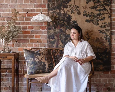 Ramble Interiors creator Alicia Doyle sitting next to a ruffled pendant and tapestry