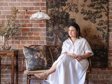 Ramble Interiors creator Alicia Doyle sitting next to a ruffled pendant and tapestry