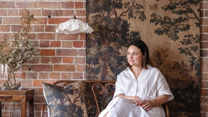 Ramble Interiors creator Alicia Doyle sitting next to a ruffled pendant and tapestry