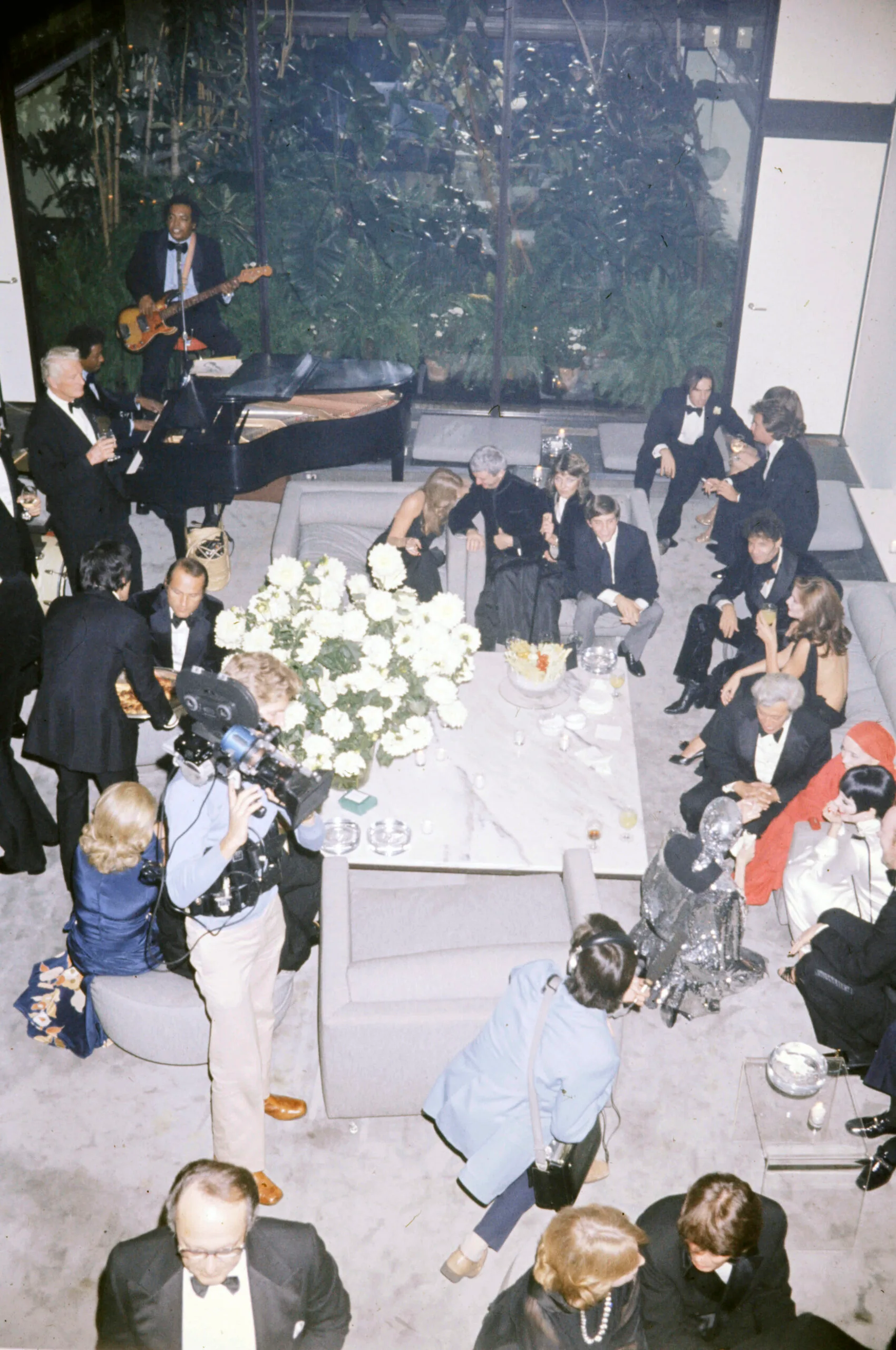 Guests attend Liz Minnelli's and Jack Haley Jr.'s first wedding anniversary party on September 15, 1975 in Halston's New York City townhouse, gathering in the grey living room around a square marble coffee table