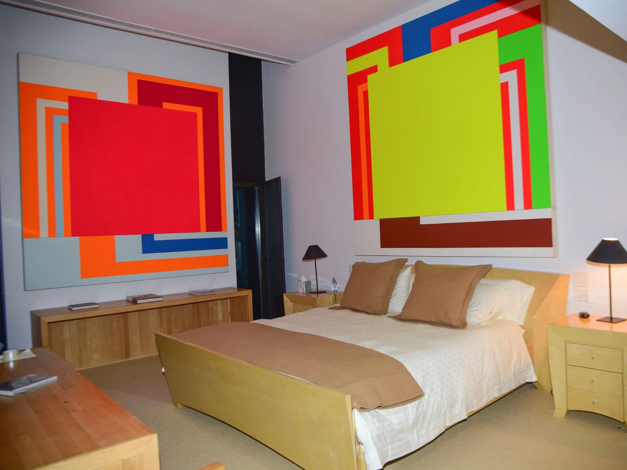 A bedroom in Halston House in 2018, fit with large scale fluorescent abstract geometric artworks on two walls