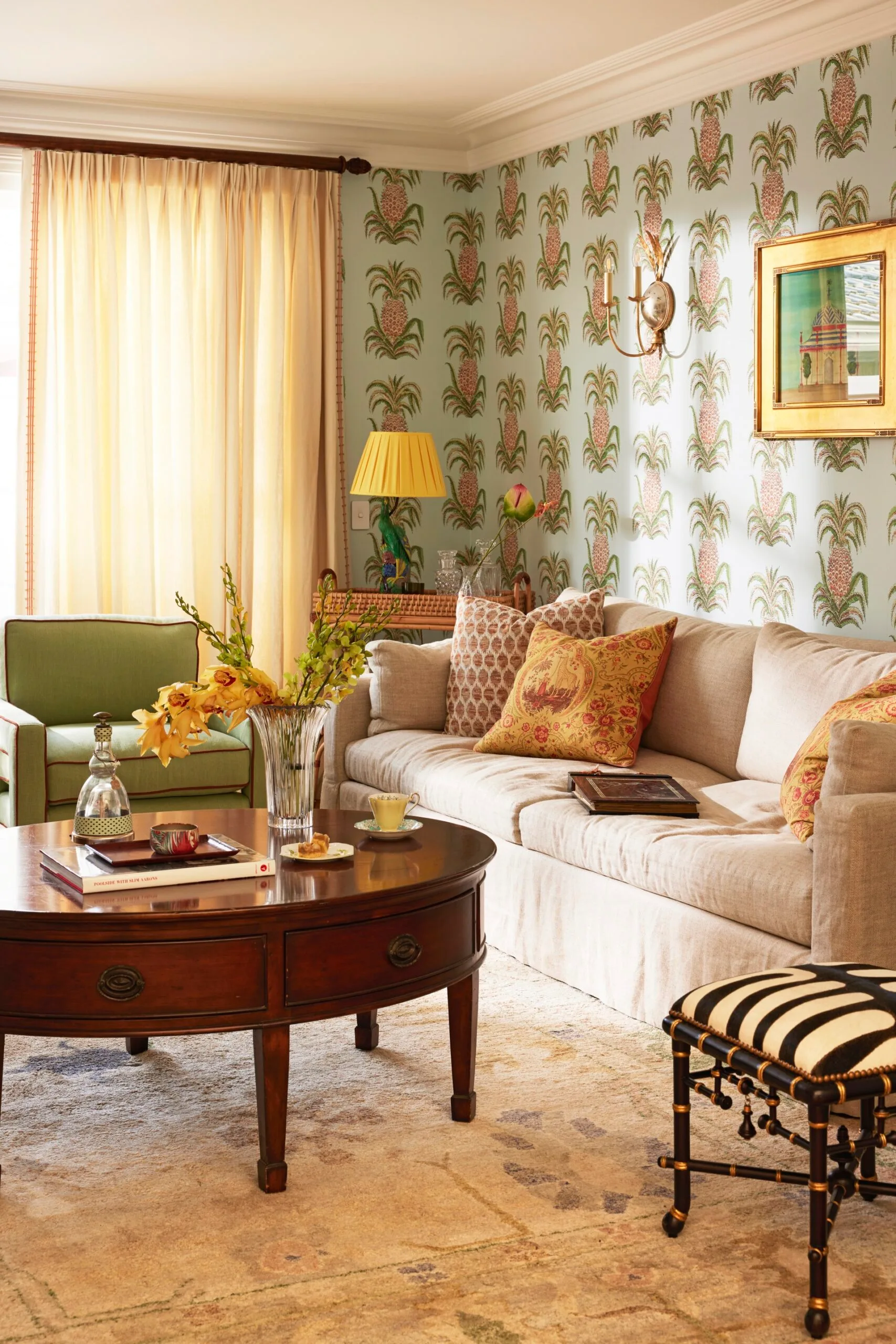 Cozy living room with patterned wallpaper, beige sofa, colorful cushions, and a wooden coffee table with decor items.