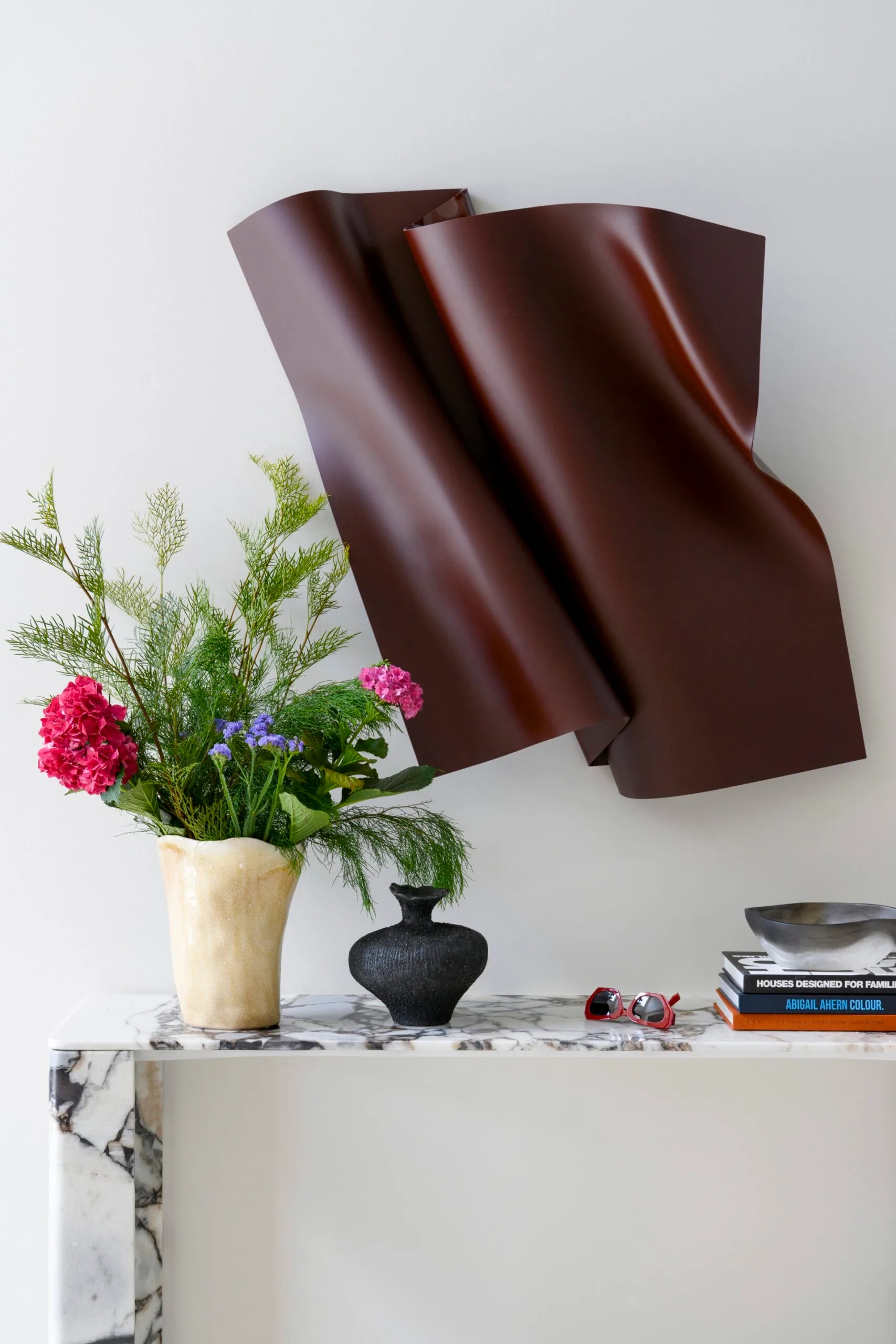 Vibrant floral arrangement on marble console with abstract wall art and books.