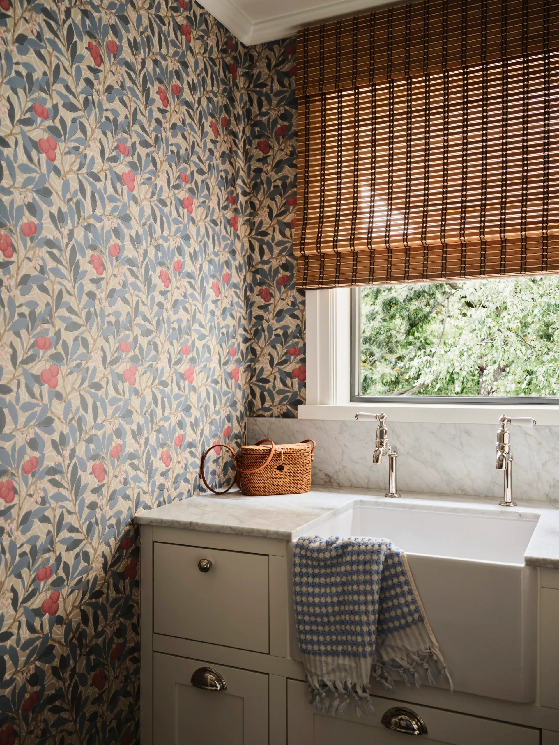 Cozy bathroom with floral wallpaper, marble sink, wicker basket, and a checkered towel on the counter.