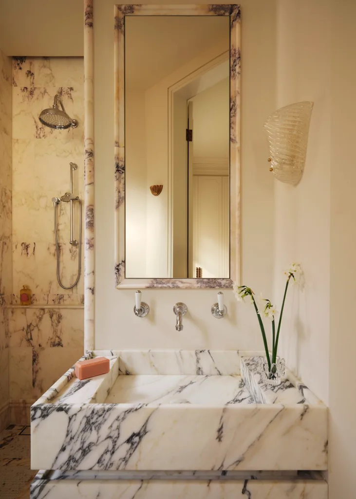 art deco wall sconce beside a mirror and above a marble vanity in an ensuite bathroom