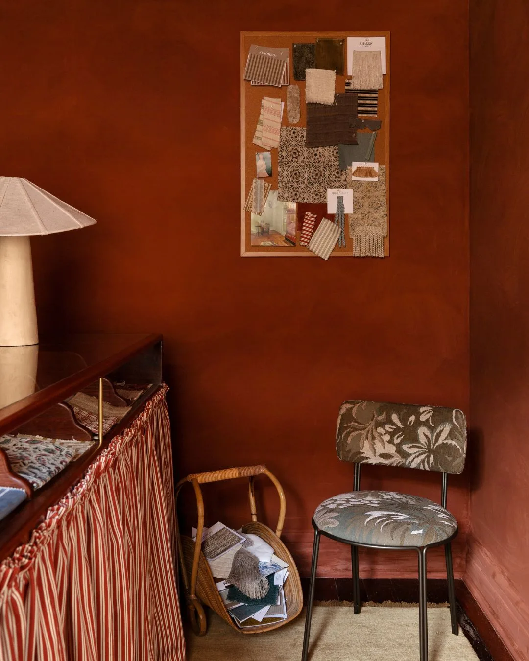 A red wall with fabric swatchest and an upholstered antique sitting chair at the Bedhead Bar in Perth