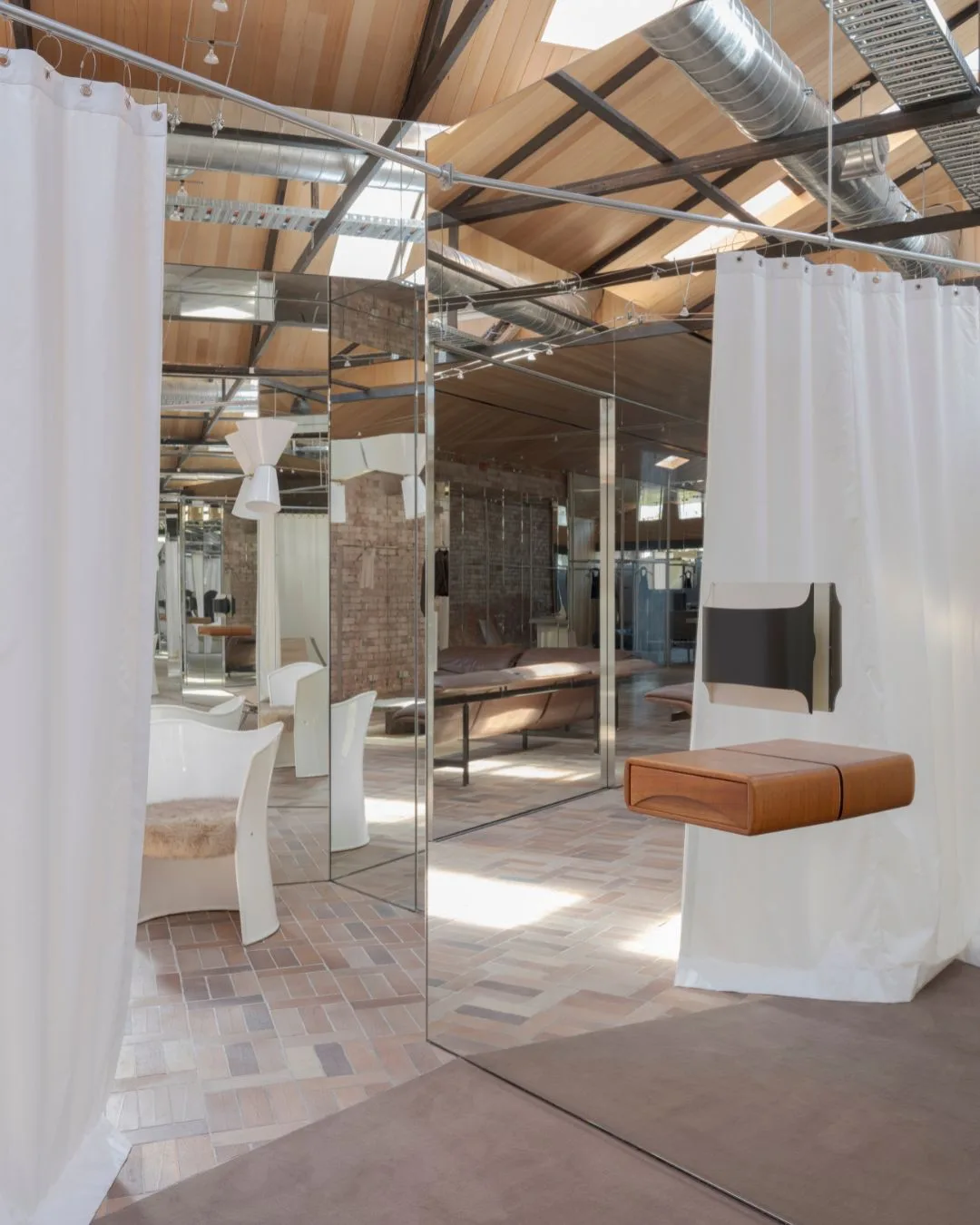 geometric mirrors and white curtains hung from metal rails in the warehouse-like space of Henne Armadale retail boutique