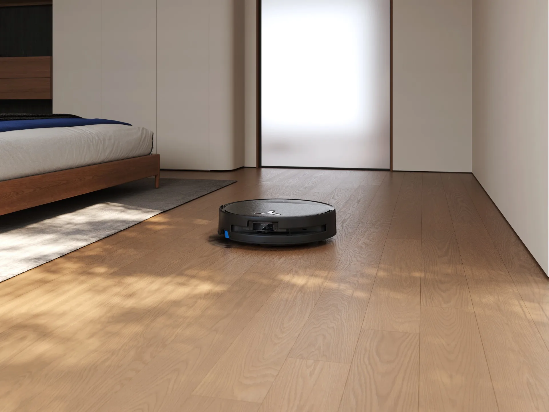 A robot vacuum cleaner moving across wooden floorboards.