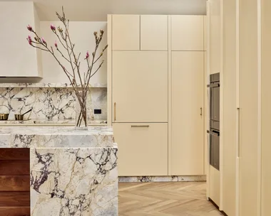 Contemporary kitchen with warm neutrals and earth tones, marble splashback, herringbone floors and a skylight.