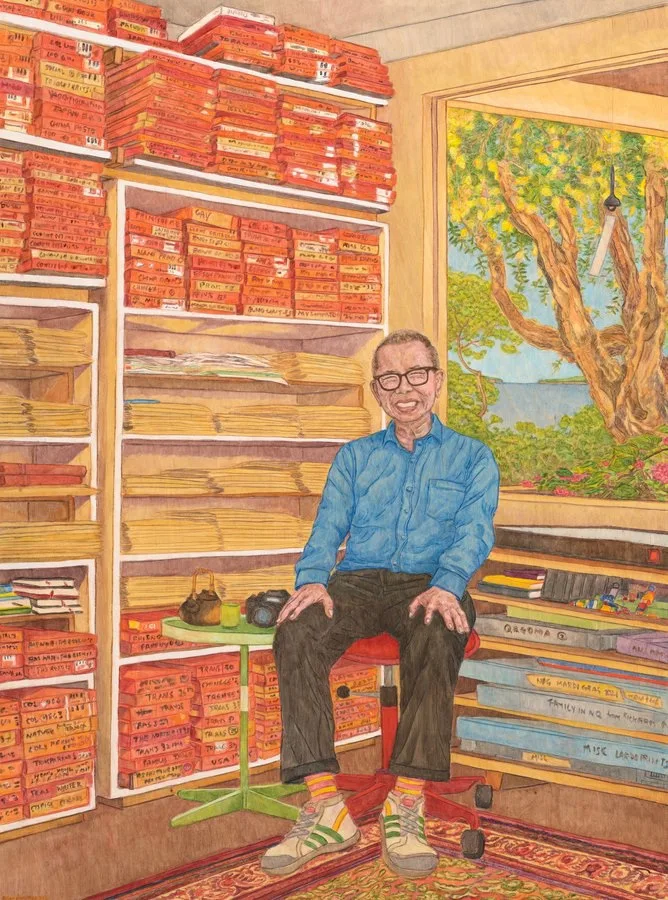 Synthetic polymer paint on carved plywood. Colourful portrait of William Yang, an artist and performer, in his studio. Bookshelves cover the walls and a window has views to a tree. The bookshelves are filled with orange books.