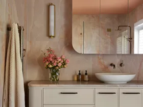 Luxurious bathroom with peach marble walls, floating vanity, vessel sink, floral arrangement, and checkered floor tiles in pinks and blues.