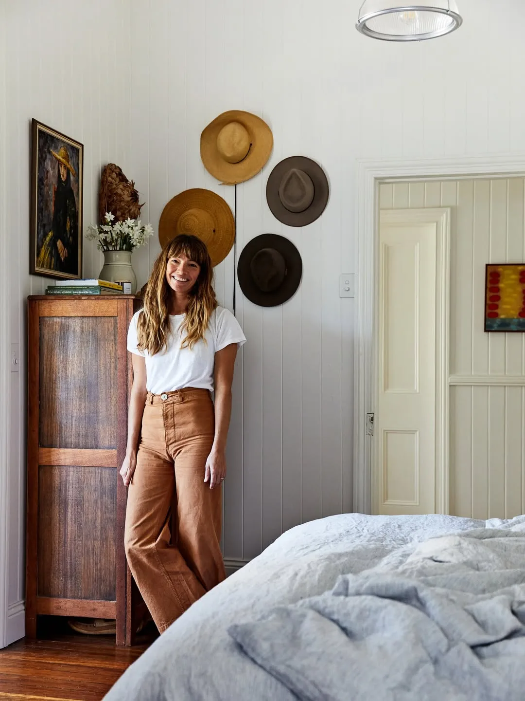 Courtney Adamo in her home next to a bed and dresser