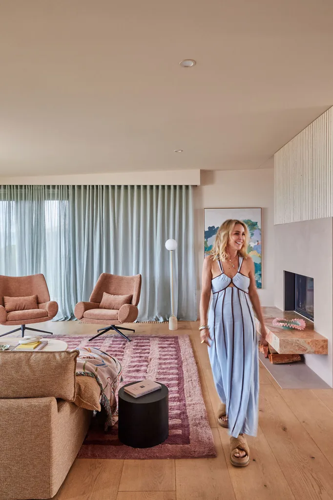 Interior stylist Julia Green walks through a stylish pink living room in a blue dress