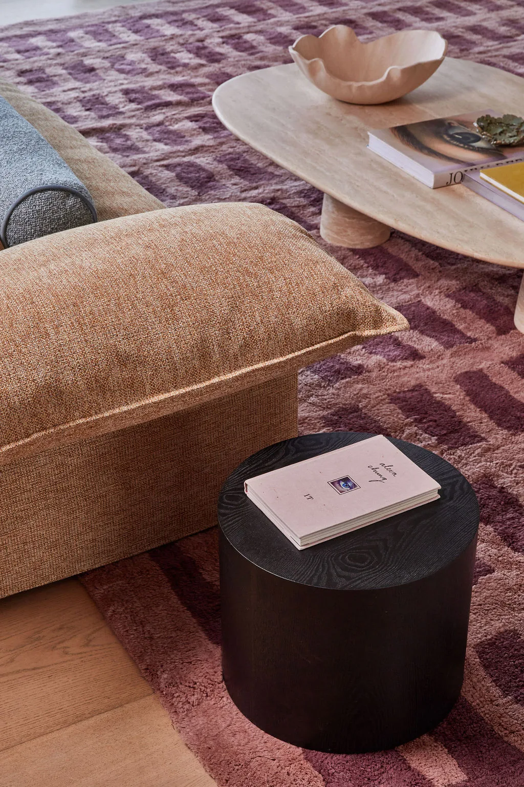 A lounge room with a pink sofa, marble coffee table and black side table that doesn't match