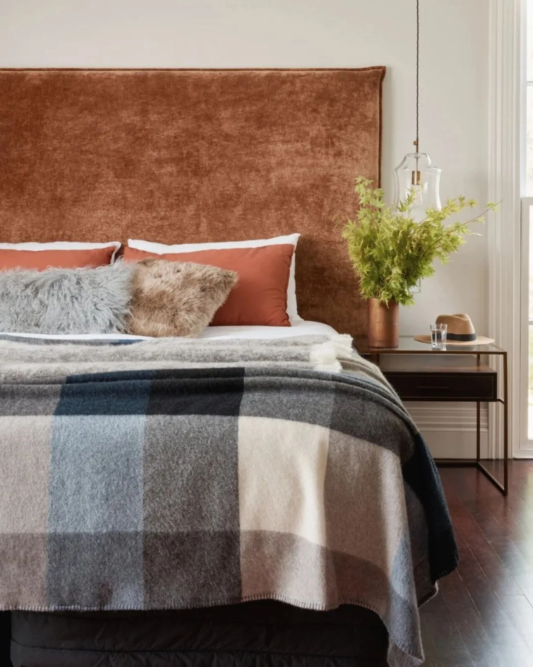 A grey, blue and white check wool blanket on the end of a stylish bed