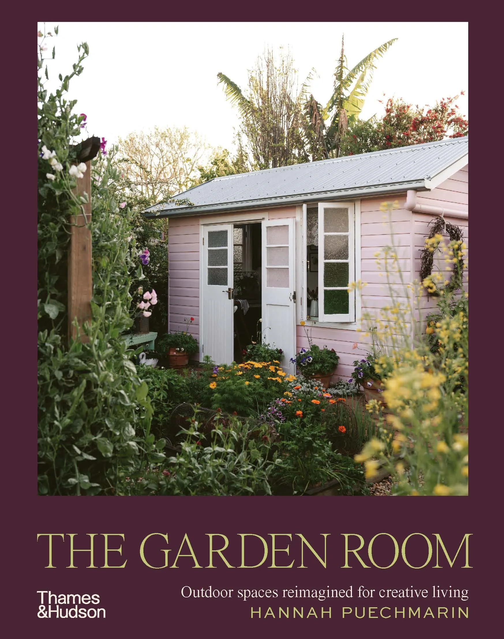 A book cover. The image depicts a pink shed, surrounded by flowers and bushes. The book title is 'The Garden Room: Outdoor Spaces Reimagined For Creative Living' by Hannah Puechmarin.
