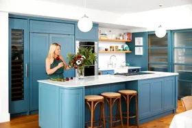 Wendy Moore in a blue kitchen arranging colourful flowers