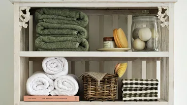 Country-style antique shelves with bathroom soaps and baskets, and towels folded three different ways