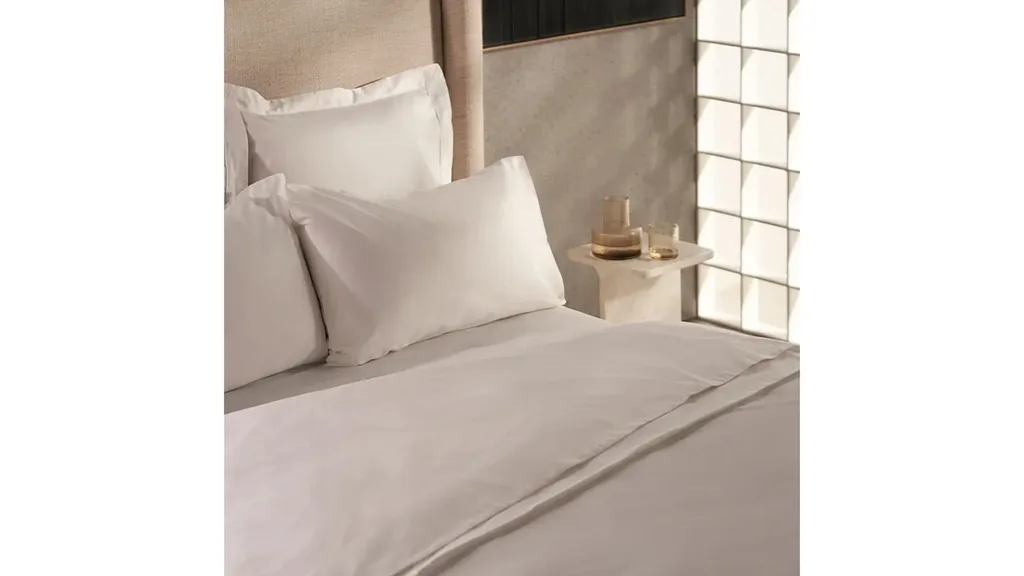 White cotton bed sheets and pillowcases on a bed.