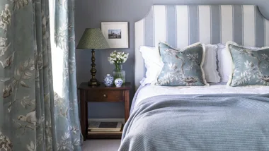 A bedroom with blue floral curtains and a queen-sized bed dressed in the best flannelette sheets in Australia