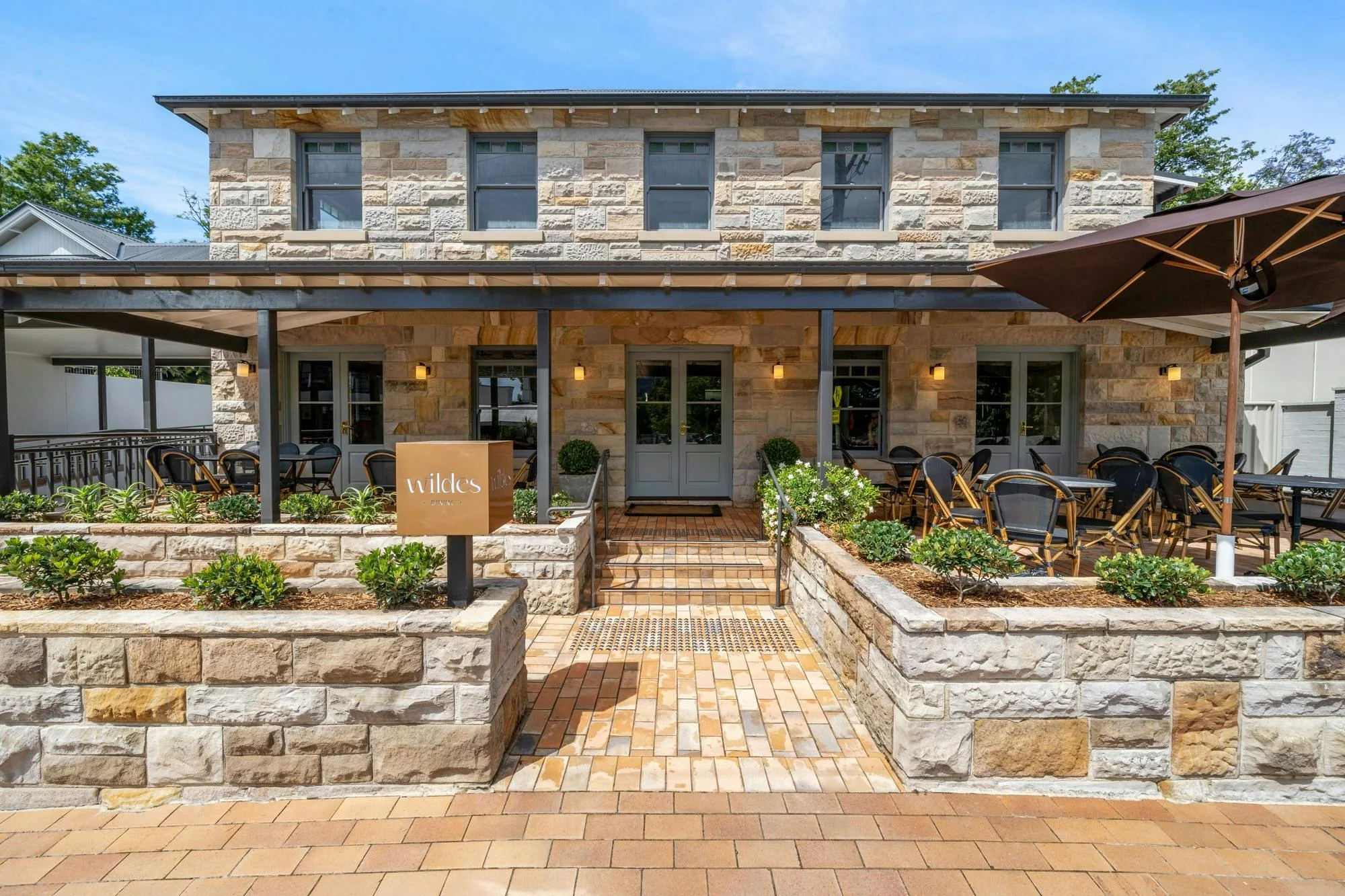 Front view of a stone building with outdoor seating and a sign reading "Wilde's."
