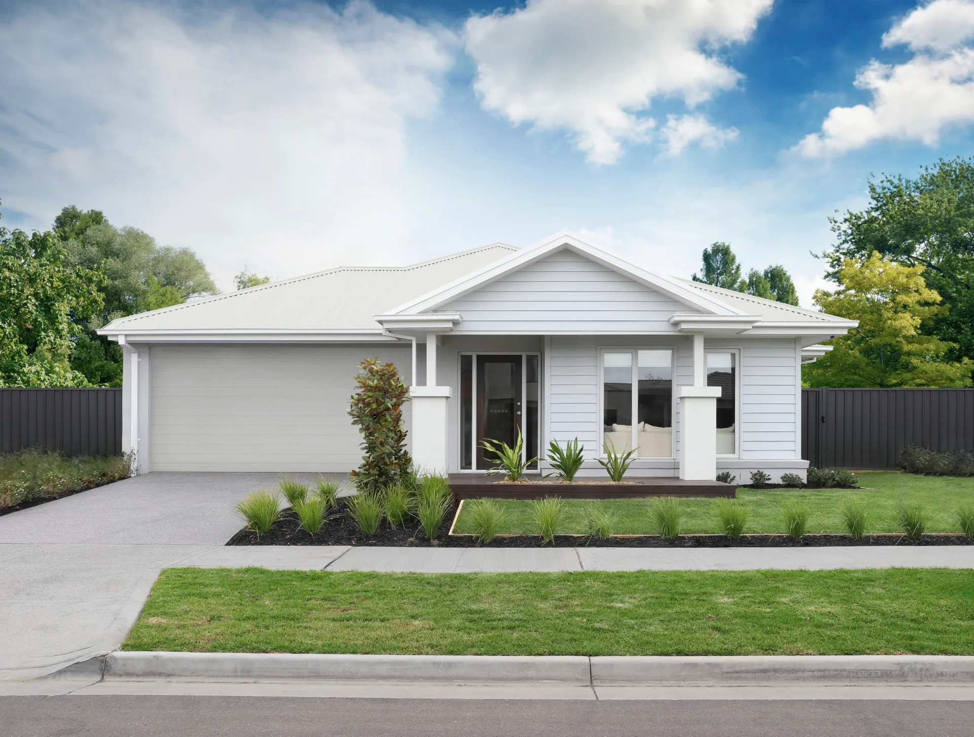 Single-story white house with a landscaped front yard, driveway, and clear blue sky background.