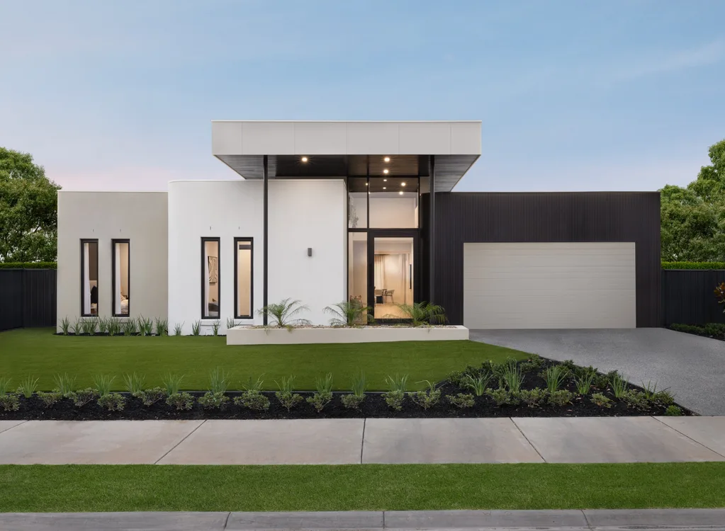 Modern single-story house with large windows, green lawn, and a driveway leading to a garage.