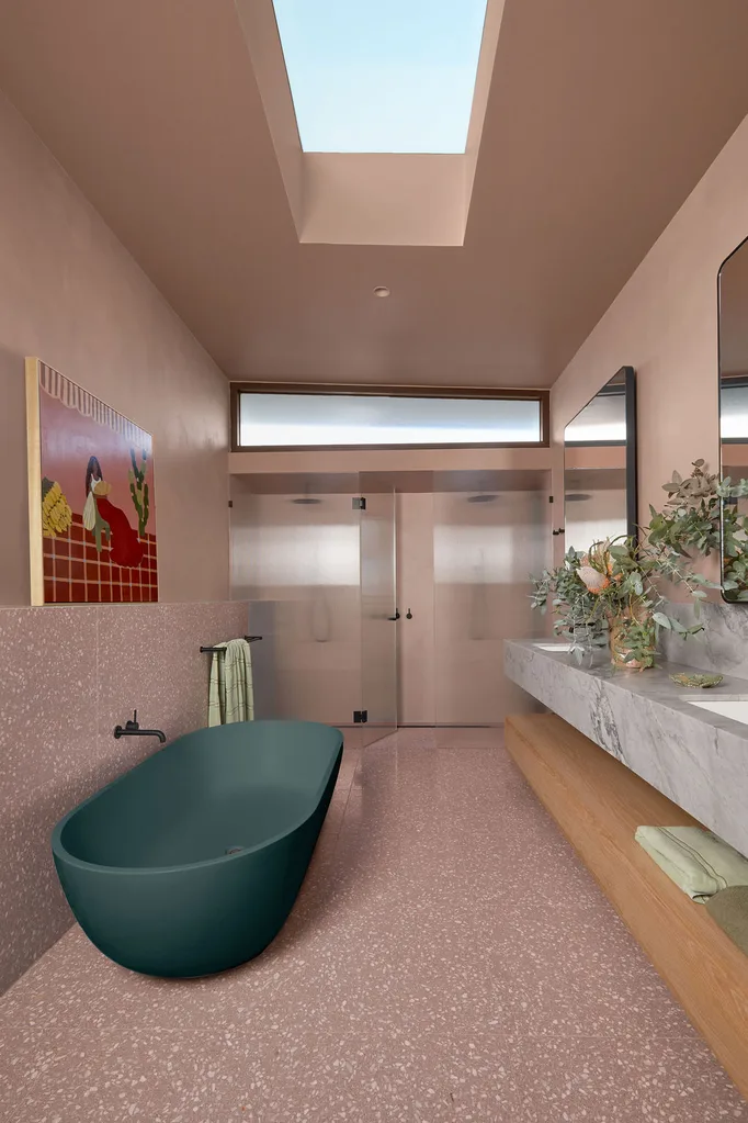 Patrick Dangerfield's bathroom features pink walls, pink terrazzo floor and a forest green freestanding bathtub.