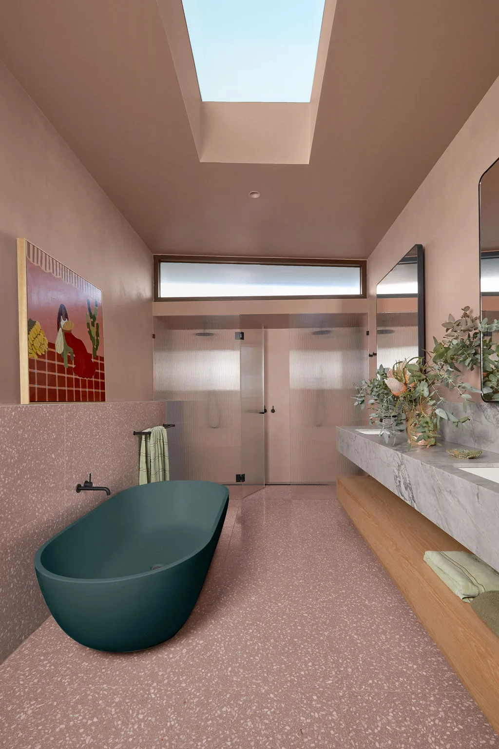 Patrick Dangerfield's bathroom features pink walls, pink terrazzo floor and a forest green freestanding bathtub. 