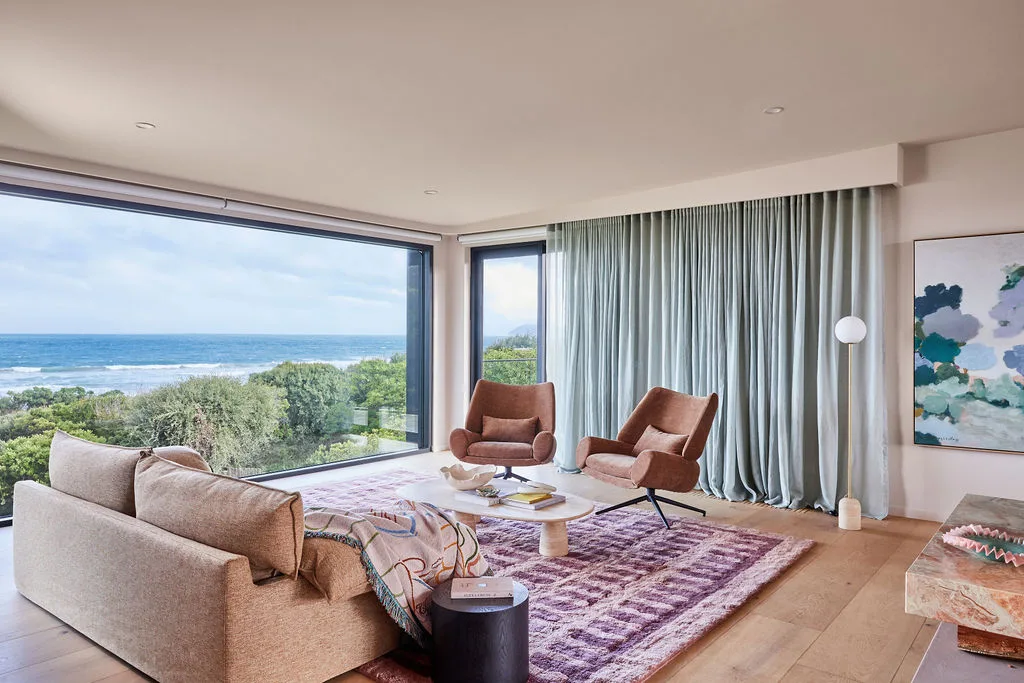Patrick Dangerfield's living room with pink furniture and rugs and a beautiful view of the ocean.