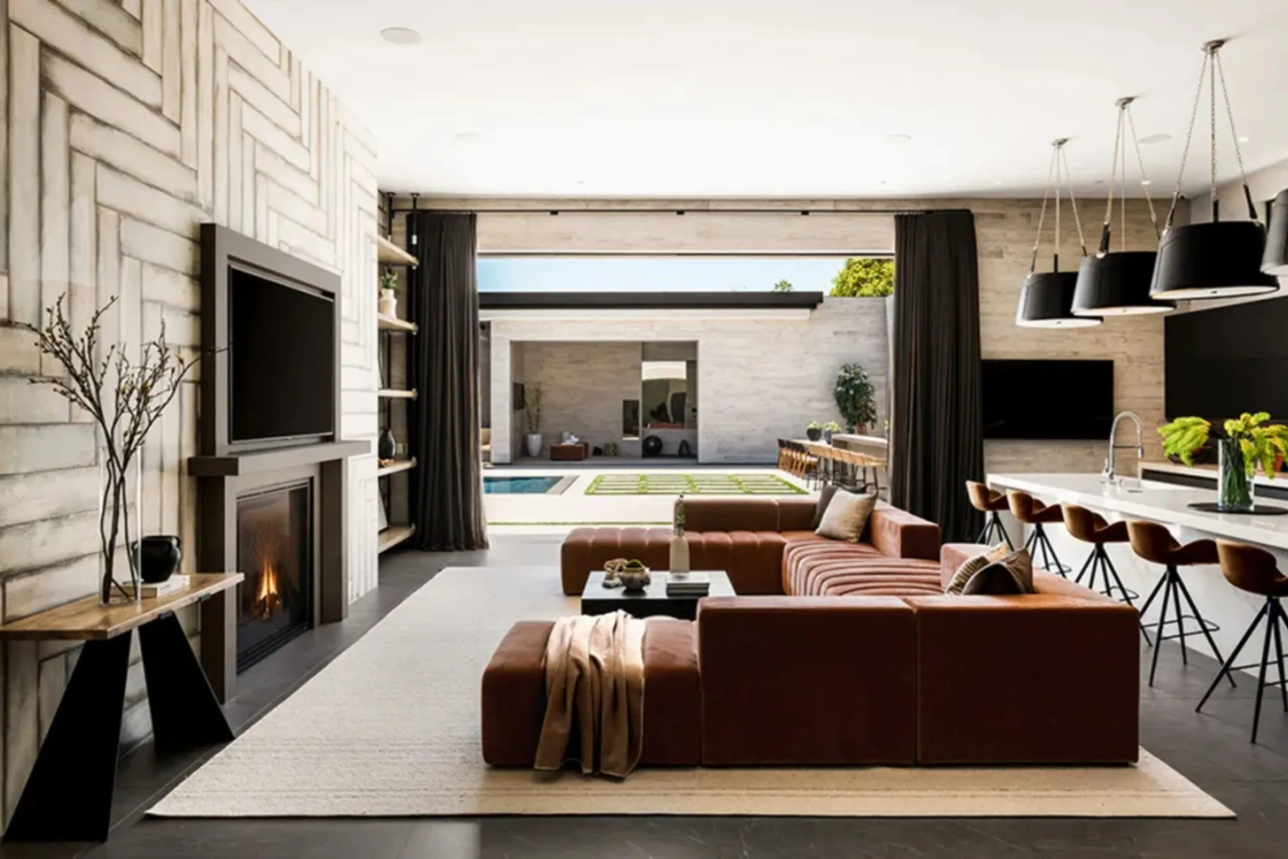 Open-plan living room and kitchen inside Kylie Jenner&rsquo;s Holmby Hills mansion, with a brown modular sofa, fireplace and large kitchen island.